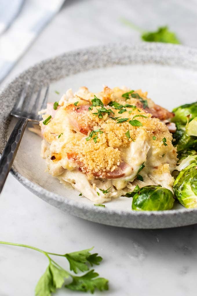 A slice of chicken cordon bleu casserole on a plate with brussels sprouts.