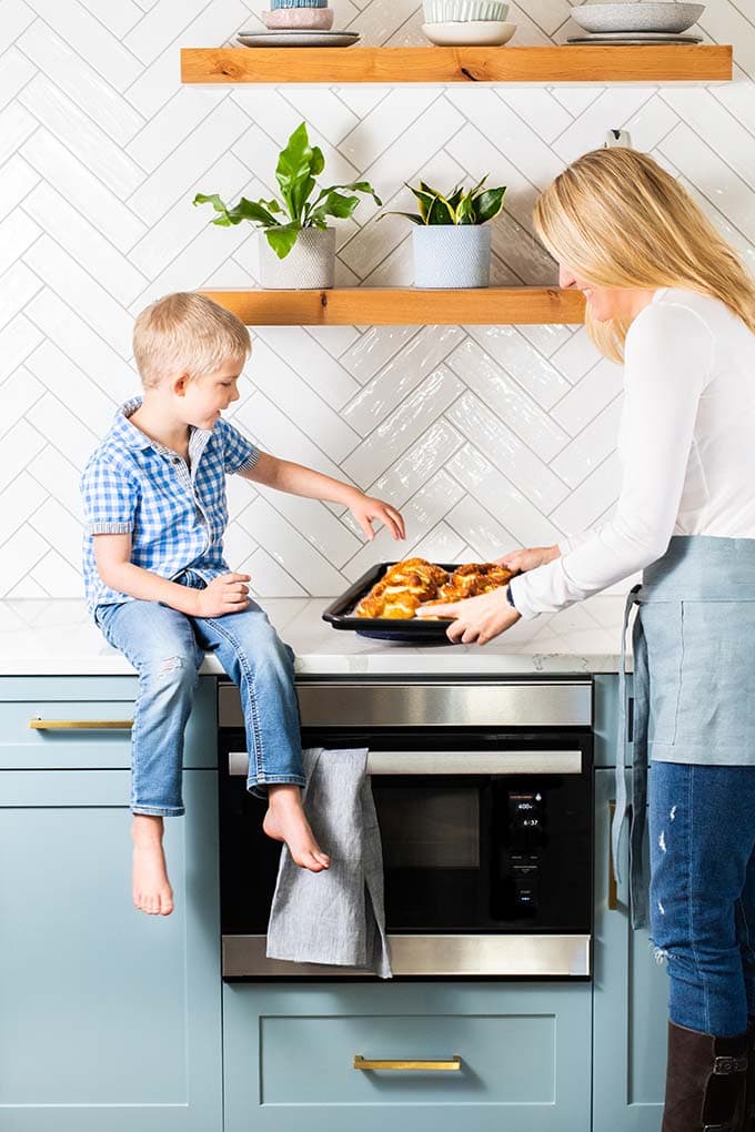 Michelle taking hot pretzels out of the oven and showing Xander.