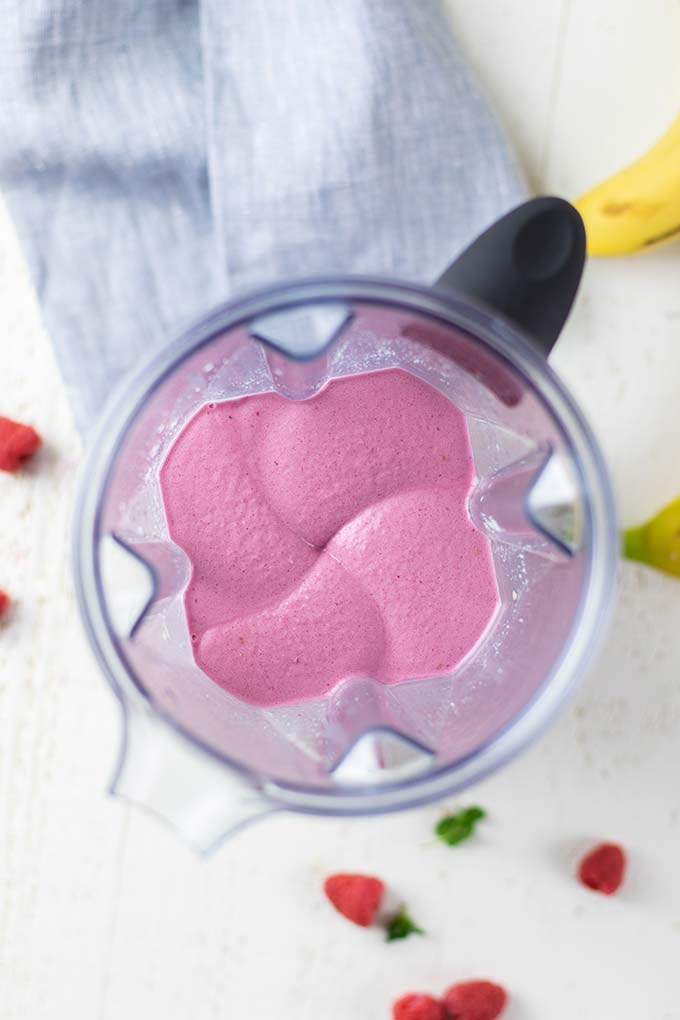 A look down into a blender with a raspberry smoothie, showing the soft texture.