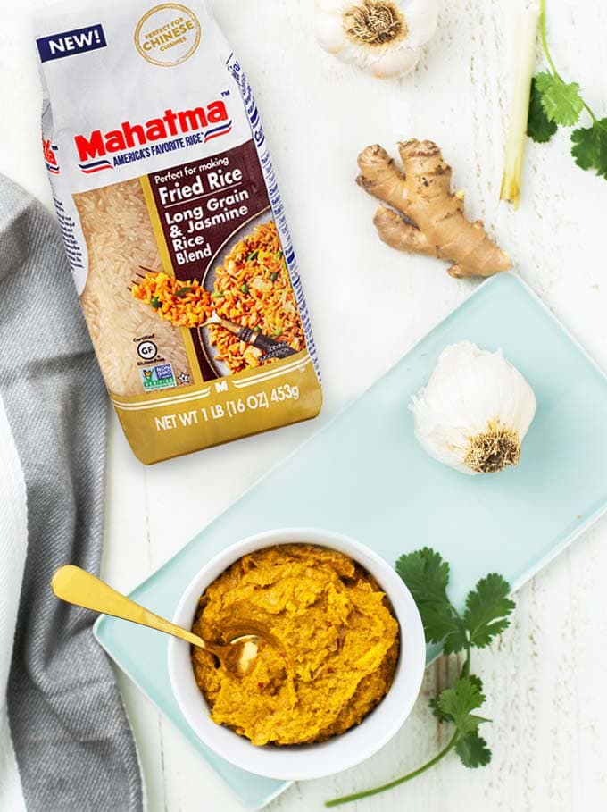 A bowl of yellow curry paste sitting next to a bag of rice.