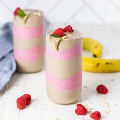 Two smoothies with layers of a SunButter and raspberry smoothie, topped with raspberries and oatmeal.