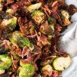 A top down view of crispy roasted brussels sprouts with big chunks of crisp bacon.