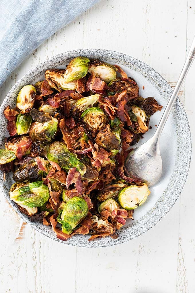 A top down view of crispy roasted brussels sprouts with big chunks of crisp bacon.