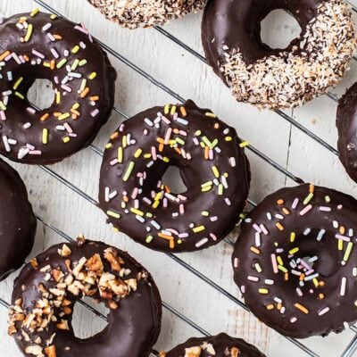 Chocolate donuts, shown glazed and decorated with coconut, pecans, and sprinkles.