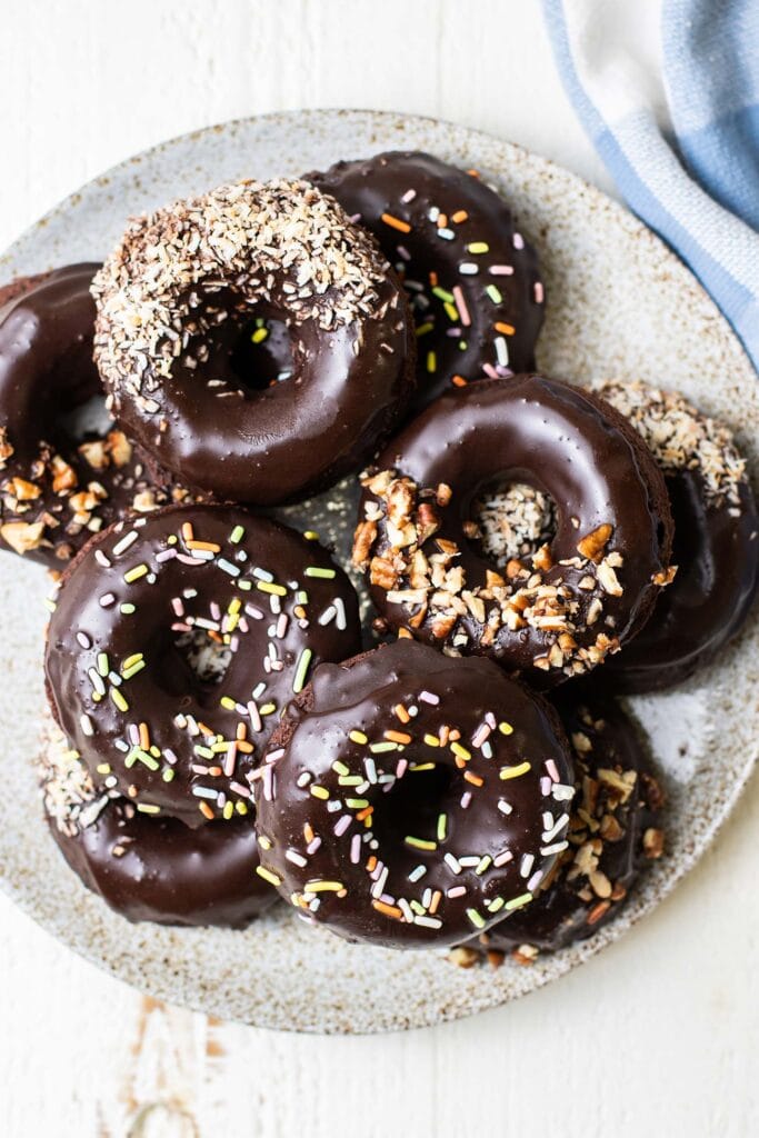 A plate of donuts decorated with coconut, pecans, and sprinkles.