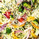 A close up of zoodles primavera shown with the veggies tossed into the mixture.