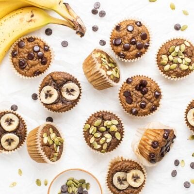 Banana Muffins topped with chocolate chips, pumpkin seeds, and banana slices.