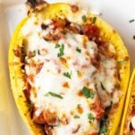 A spaghetti squash half filled with sauce and topped with mozzarella cheese.