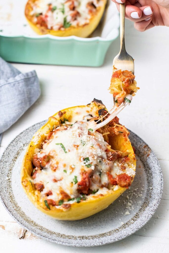 A spaghetti squash boat on a plate with a fork pulling away a bite.