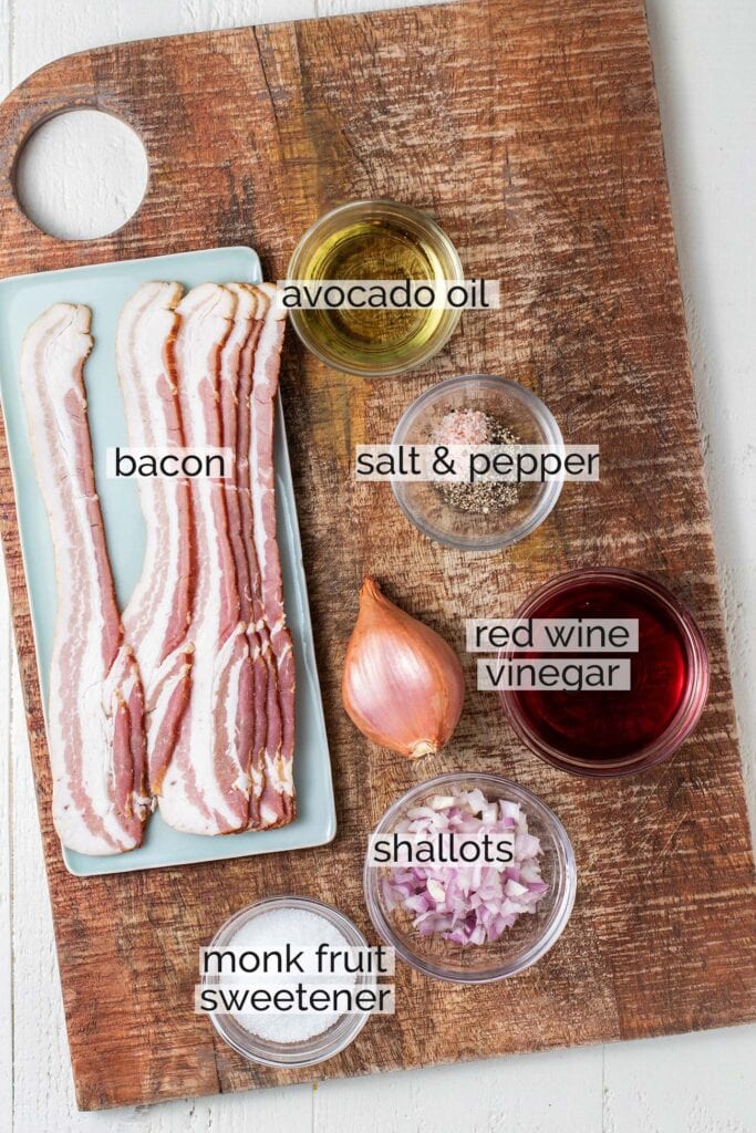 The ingredients needed for hot bacon dressing sitting on a cutting board with labels.
