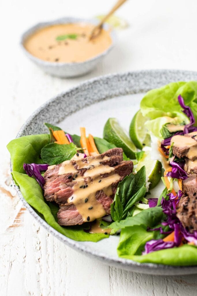 A side view of a beef lettuce wrap drizzled with a nutty sauce.