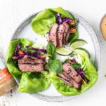 Leaves of lettuce filled with colorful veggies and thinly sliced steak.