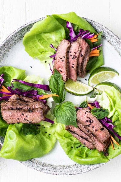 Leaves of lettuce filled with colorful veggies and thinly sliced steak.