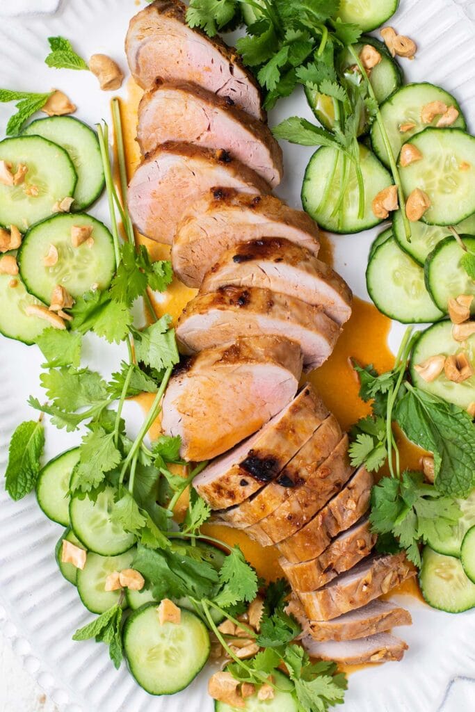 A pork tenderloin shown drizzled with a marinade on a platter.