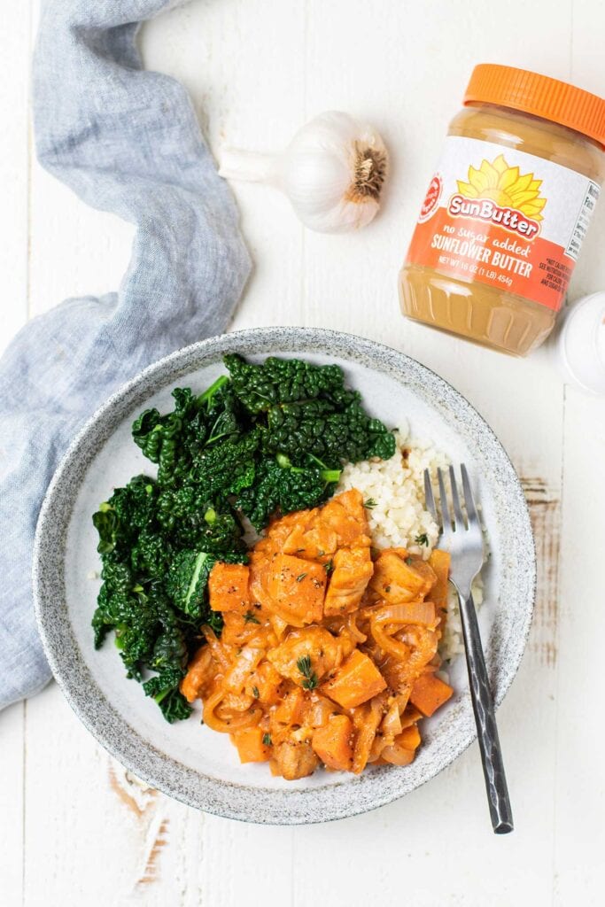 A plate of African Chicken Stew shown with a jar of SunButter.