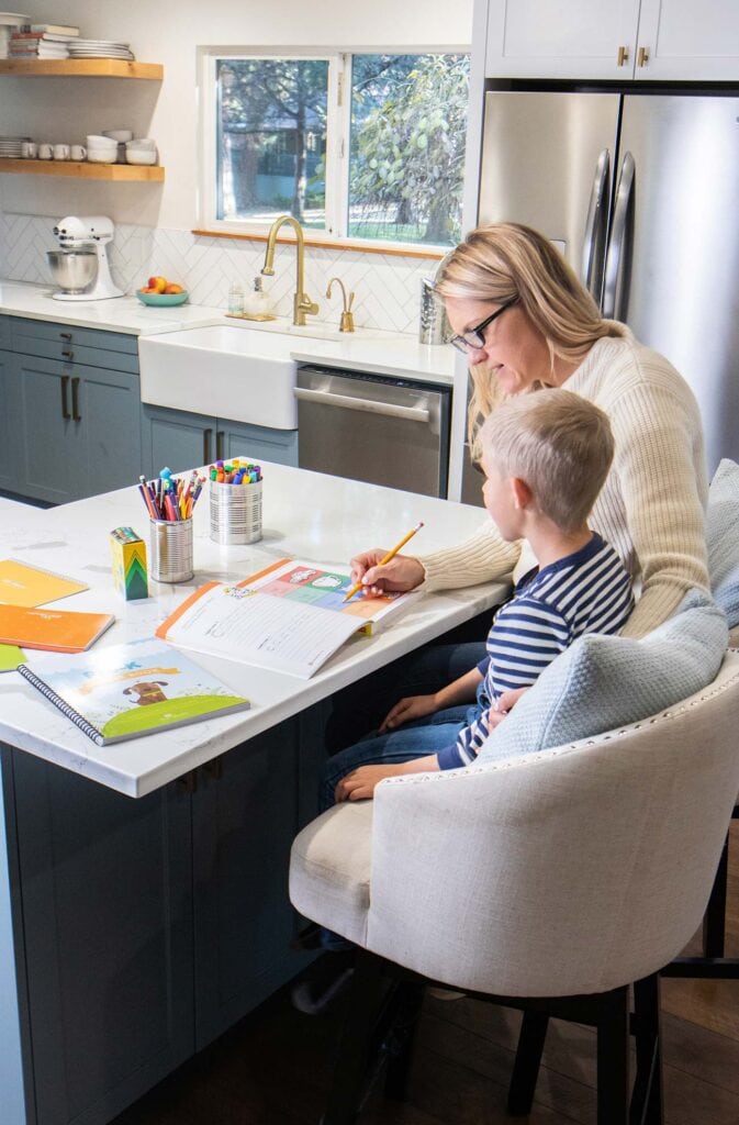 MOm and son sitting together doing homework in a kitchen.