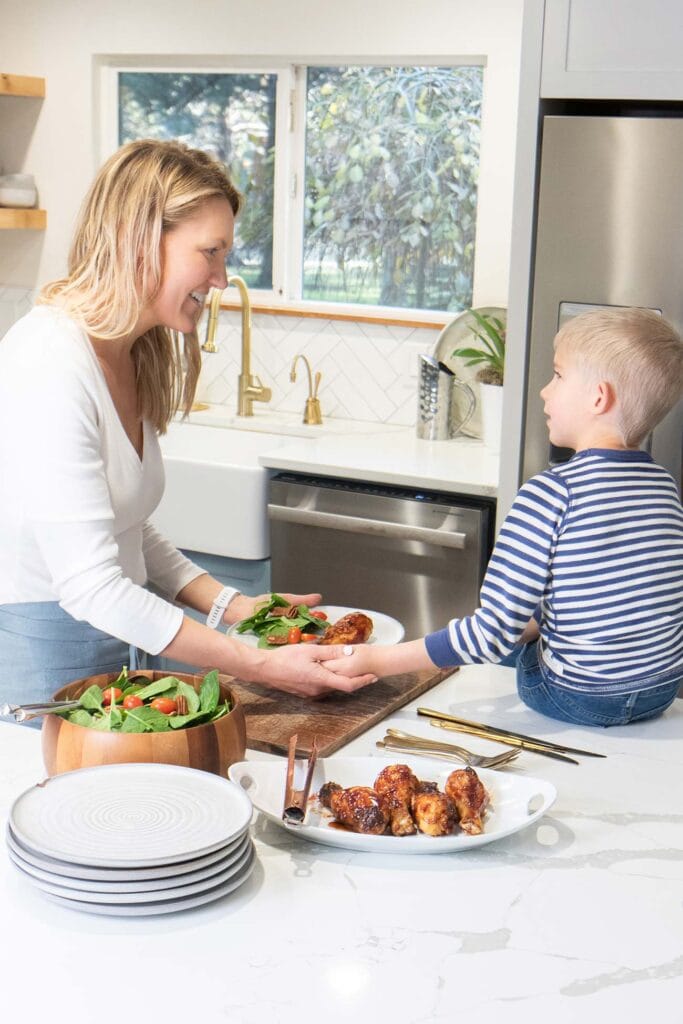 A mother and son serving dinner on a kitchen island.