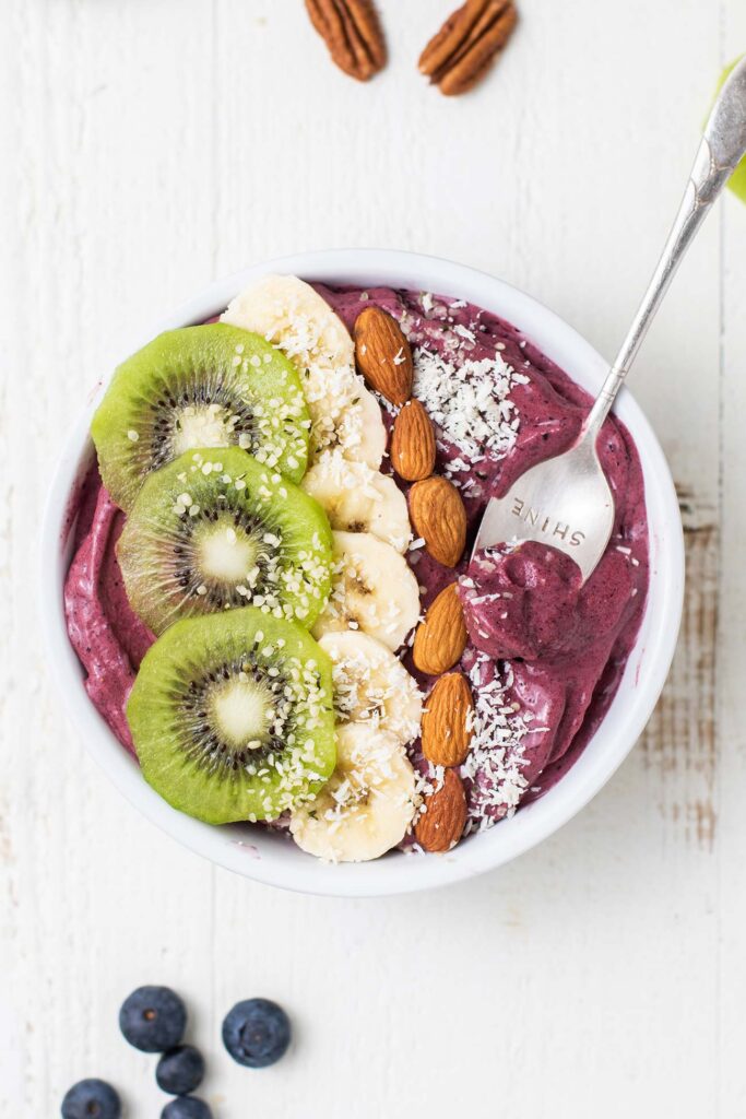 A thick purple smoothie bowl topped with kiwi and banana.