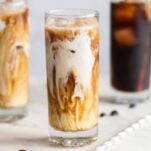 Three glasses of iced cold brew with coconut milk swirling in to the coffee.