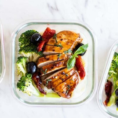Balsamic vinegar chicken breasts shown sliced and packed with broccoli in meal prep boxes.