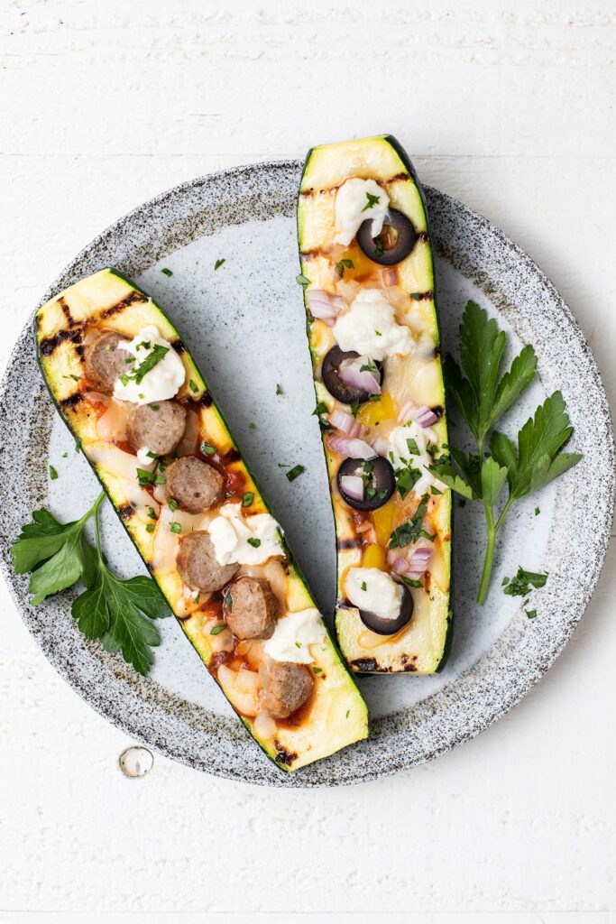 Two zucchini pizza boats shown served on a white plate.