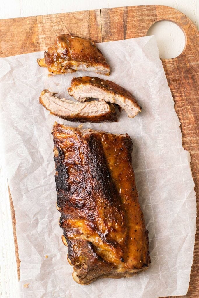 A rack of ribs shows with a couple of the top ribs cut off.