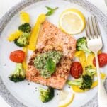 A close up look at pesto salmon served with vegetables.