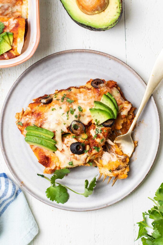 A fork taking a bite of a sweet potato and turkey enchilada.