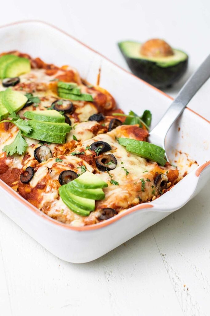 A spatula serving turkey sweet potato enchiladas.