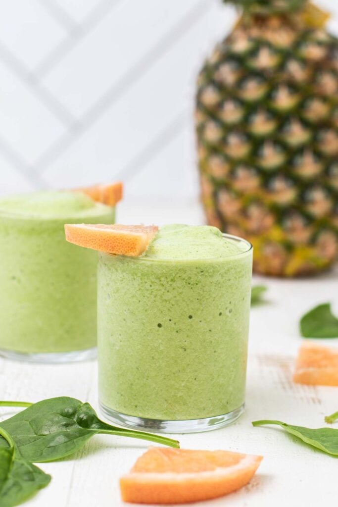 A vibrant green fat loss smoothie shown in front of a pineapple.