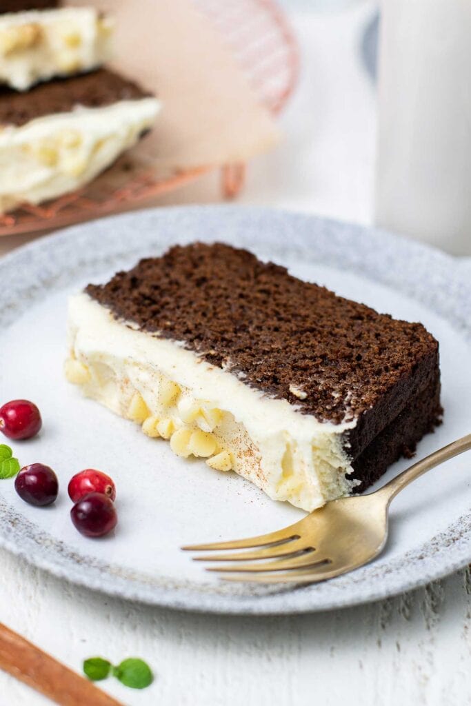 A slice of gluten free gingerbread shown topped with a white chocolate marscapone.