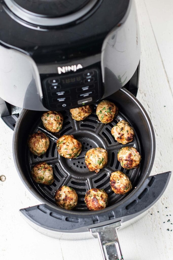 Meatballs shown browned in an air fryer.