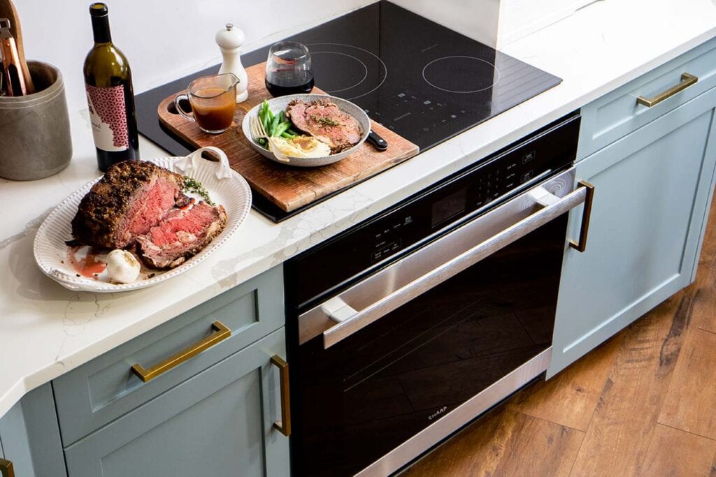 A prime rib dinner sitting on top of a Sharp European Convection Oven.