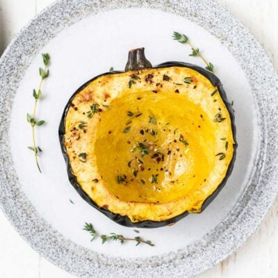 A roasted acorn squash on a white plate.