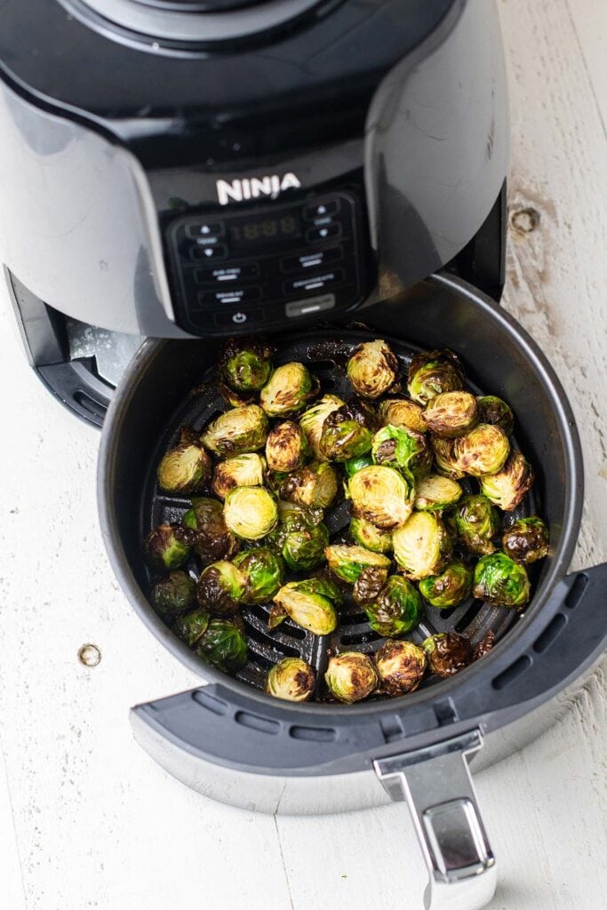 Brussels sprouts shown in an air fryer.