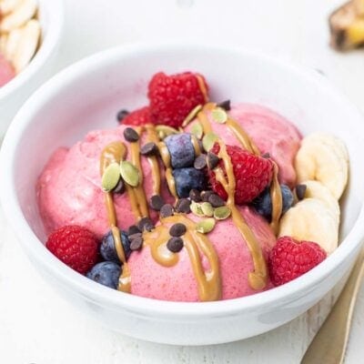 Bright pink ice cream topped with SunButter and berries.