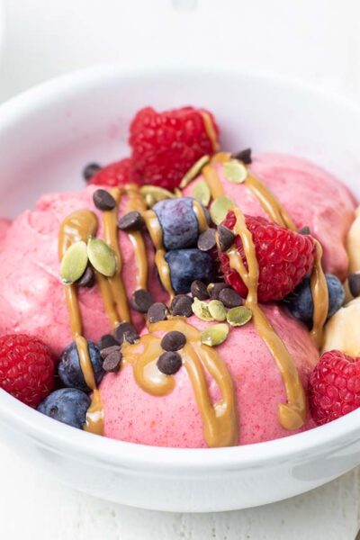 Bright pink ice cream topped with SunButter and berries.