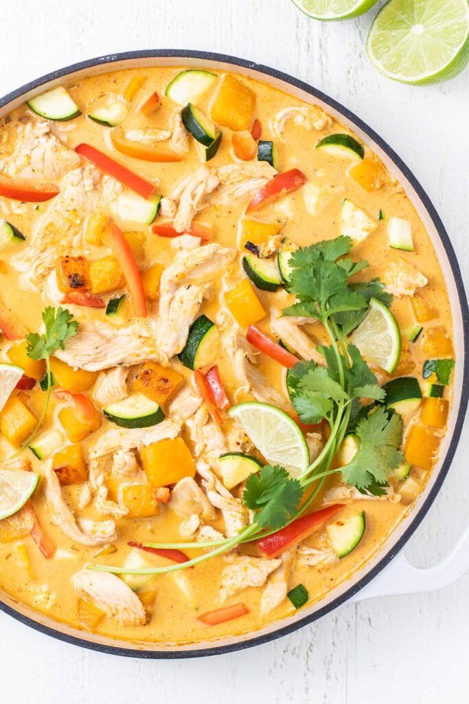A large skillet with a Thai red curry with butternut squash and chicken.
