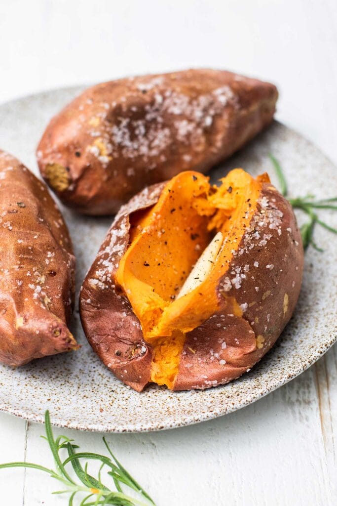Sweet potatoes shown on a plate with a crispy, salted skin.