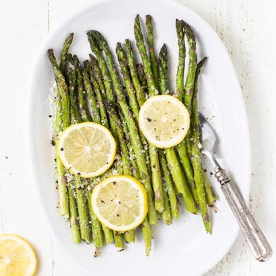 A white plate shown with asparagus cooked in an air fryer.