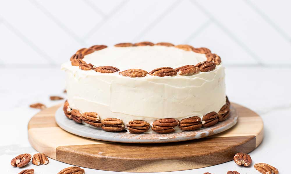 A hummingbird cake shown decorated with whole pecans.