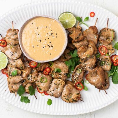A platter with Pork Satay served with a peanut dipping sauce.