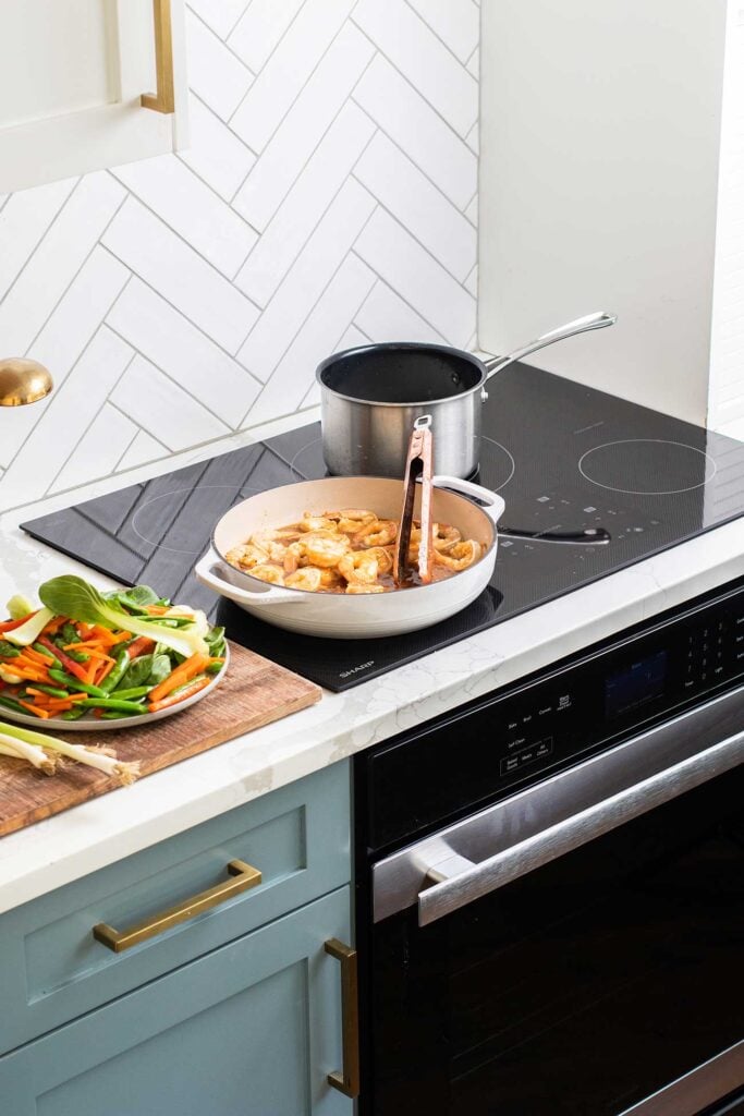 The sharp induction cooktop shown with shrimp and rice cooking.