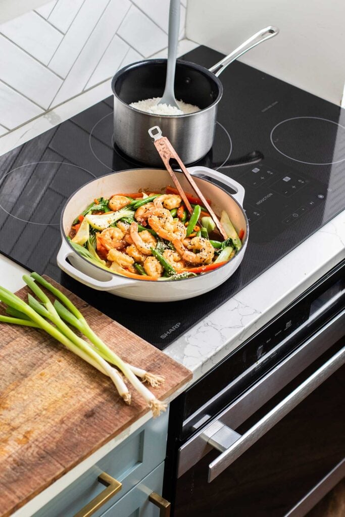 A shrimp stir fry and a pot of rice sitting on the Sharp Induction Cooktop.