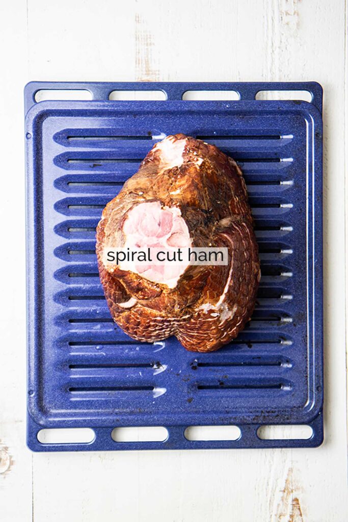 A spiral cut ham shown on a blue broiler pan.
