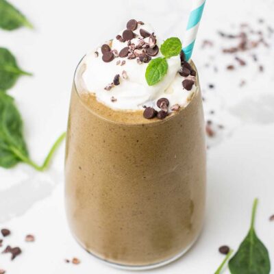 A green smoothie with coffee and chocolate shown garnished with whipped cream.