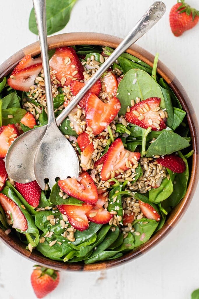 A top down look at a summery salad with spinach and strawberries.