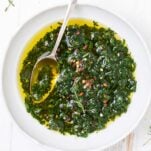 A close up look at a white bowl filled with a vibrant green chimichurri sauce.