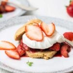 A gluten free almond flour shortcake topped with whipped cream and strawberries.