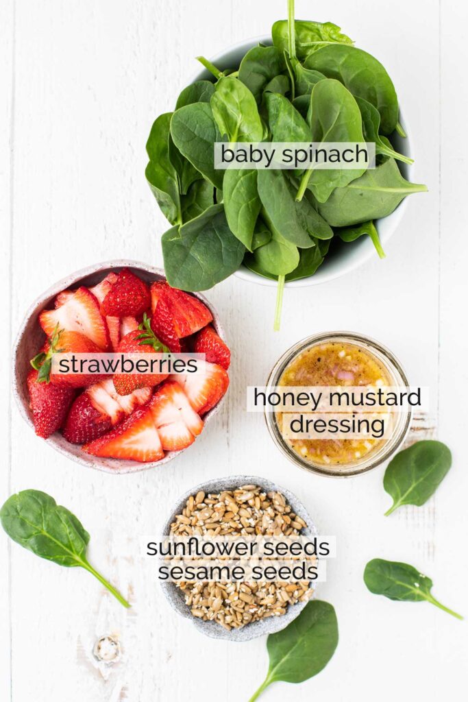 The ingredients needed to make a strawberry spinach salad.